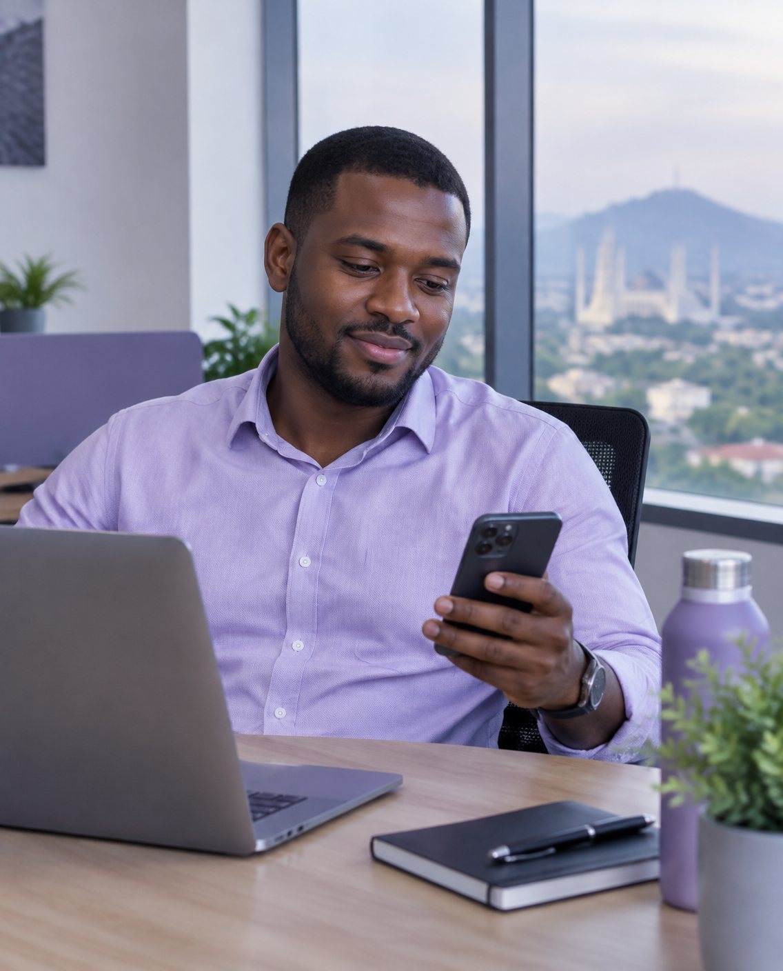 A man smiling at his phone at his office desk
